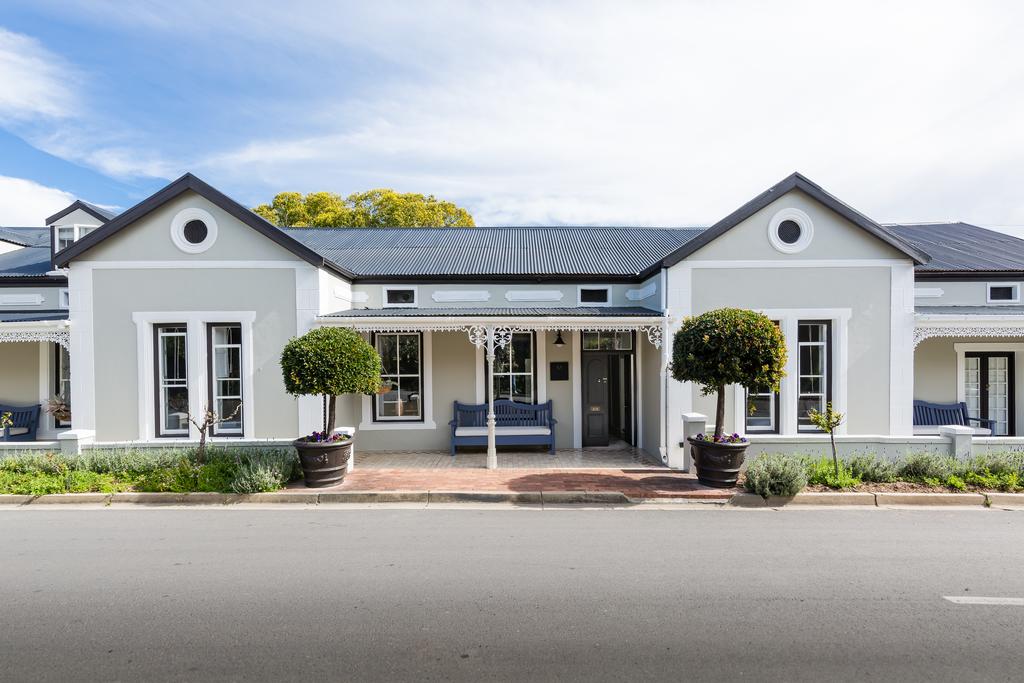 A large white house with a porch and trees in front of it.
