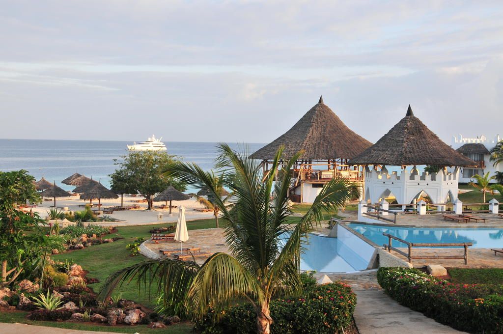 A swimming pool surrounded by palm trees with a view of the ocean
