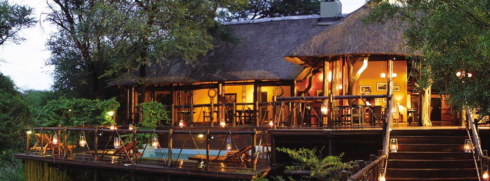 A house with a thatched roof is lit up at night