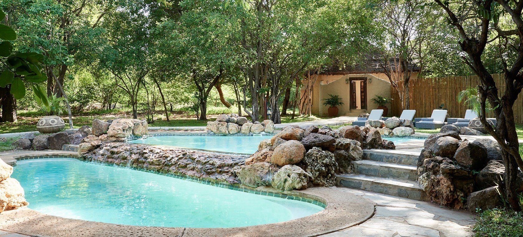 A large swimming pool surrounded by rocks and trees