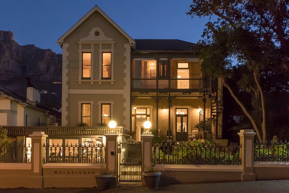 A large house is lit up at night with a mountain in the background