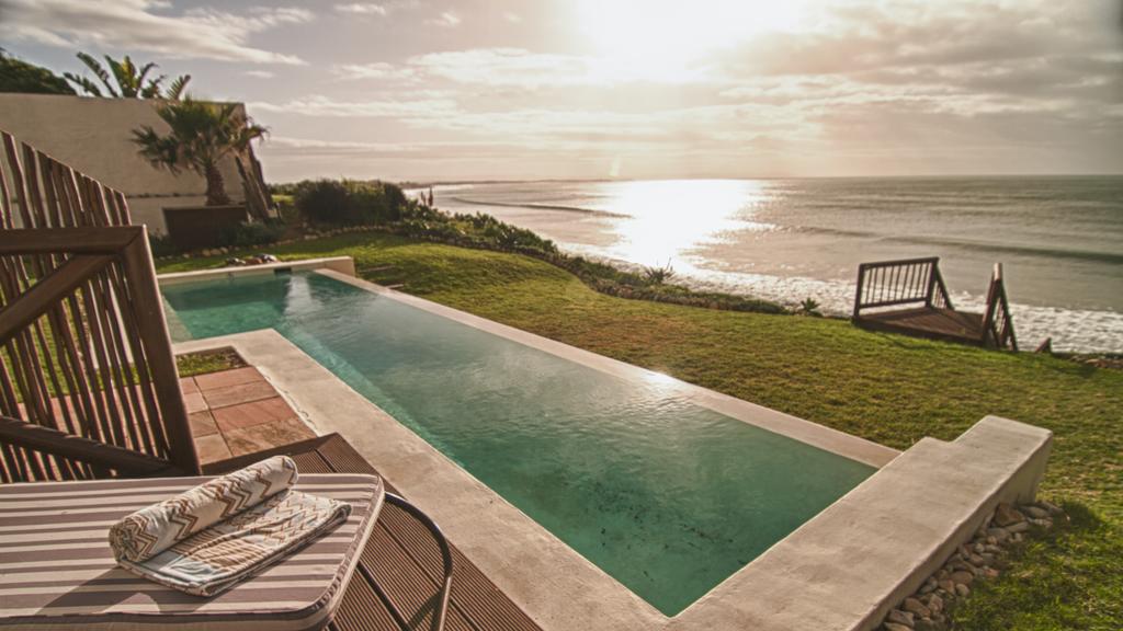 There is a swimming pool in the backyard of a house with a view of the ocean.