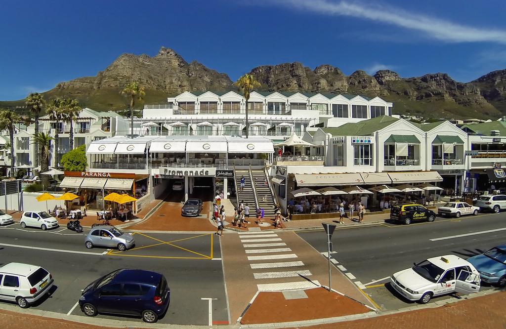 Cars are parked in front of a building with mountains in the background
