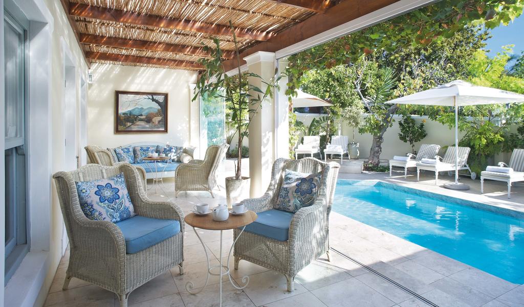 A patio with chairs and a table next to a swimming pool