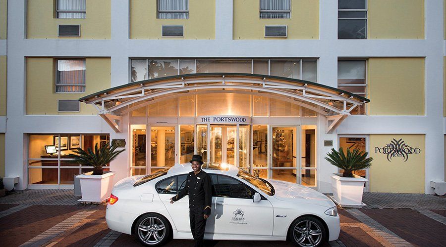 A man is standing next to a white car in front of a building.