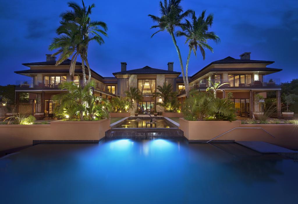 A large house with a pool in front of it at night.