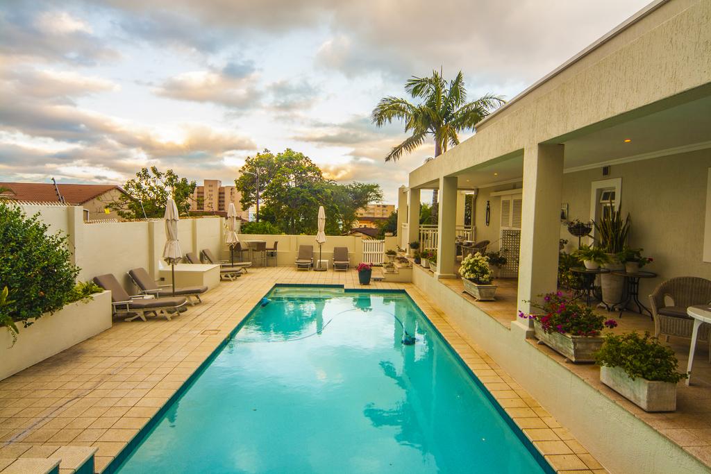 There is a large swimming pool in the backyard of a house.