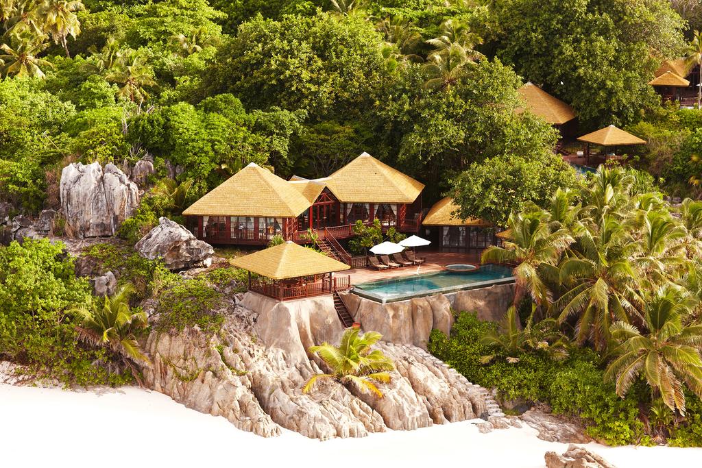 An aerial view of a house with a pool surrounded by trees