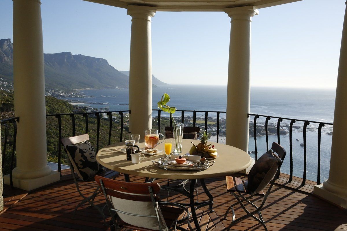A table and chairs on a balcony overlooking the ocean