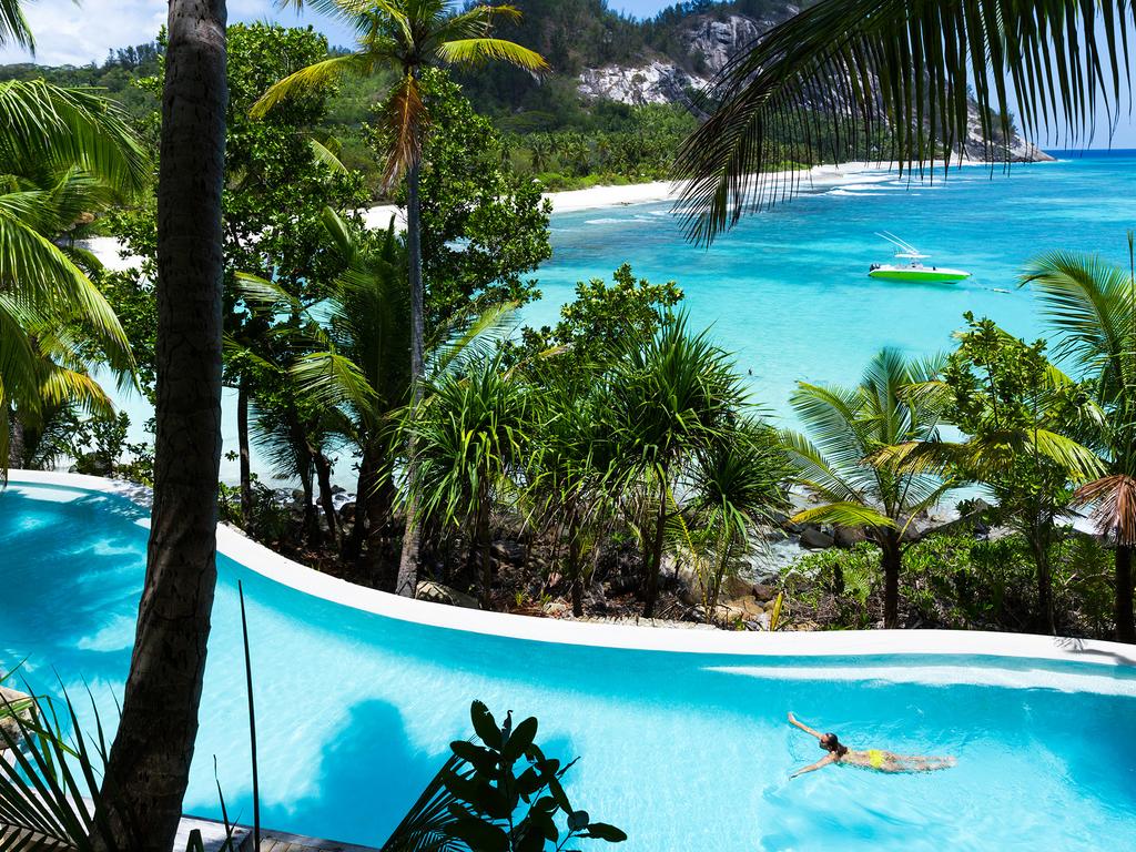 A person is swimming in a pool overlooking the ocean