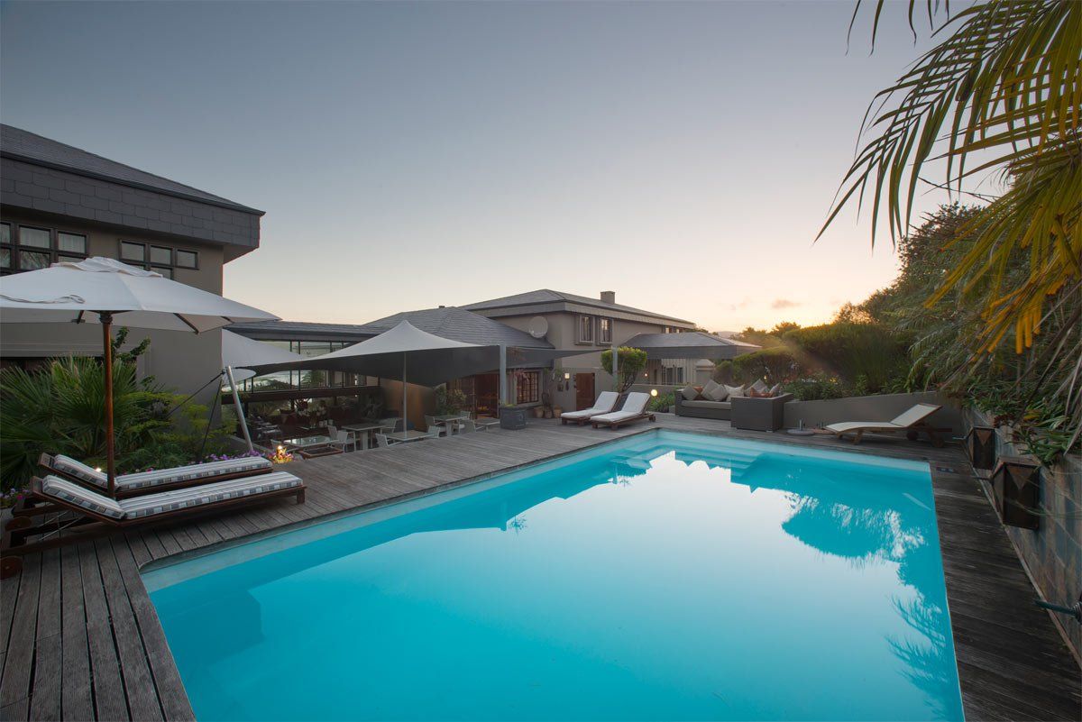 A large swimming pool with umbrellas and chairs around it