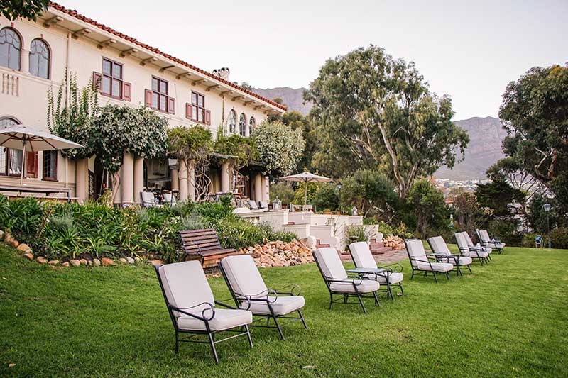 A row of chairs are sitting in the grass in front of a large building.