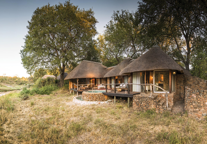 A house with a thatched roof sits in the middle of a field