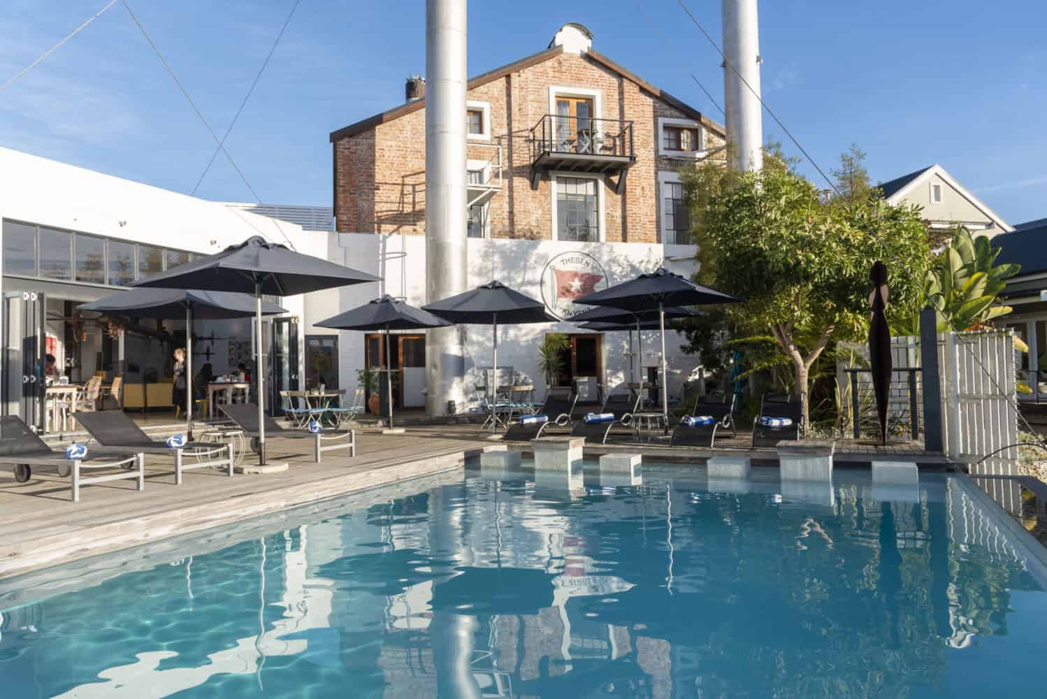 A large swimming pool with umbrellas in front of a building.