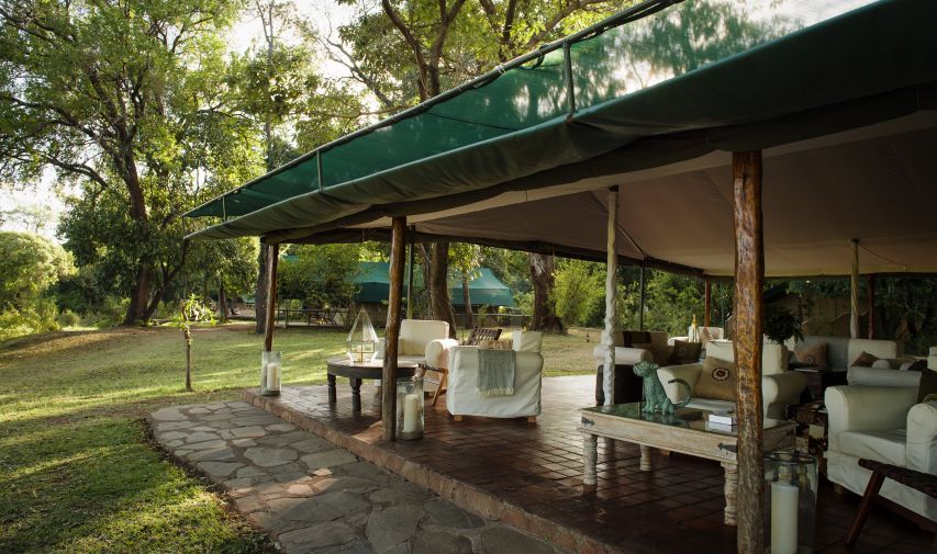 A large tent with a green awning is sitting in the middle of a lush green field.