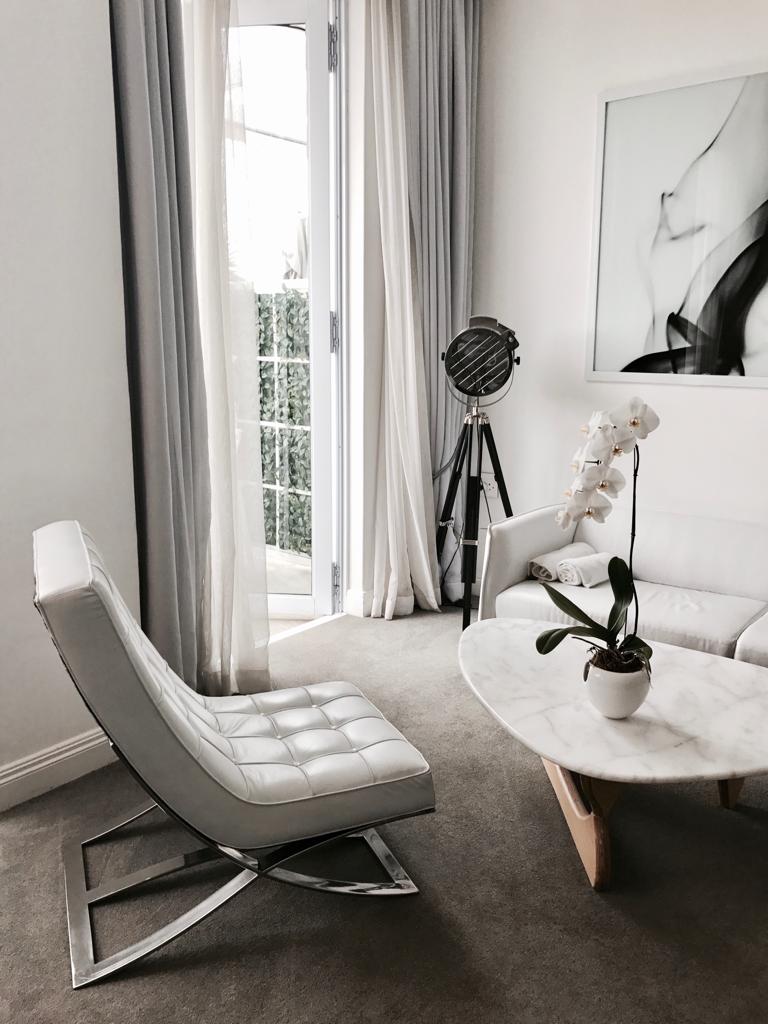 A living room with a couch , chair , coffee table and a painting on the wall.