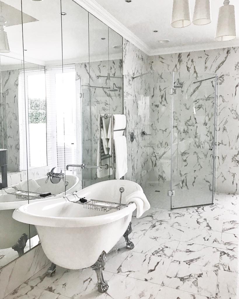 A bathroom with a claw foot tub , sink , shower and mirror.