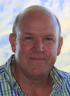 A bald man wearing a plaid shirt is smiling for the camera.