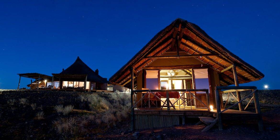 A small house with a thatched roof is lit up at night.