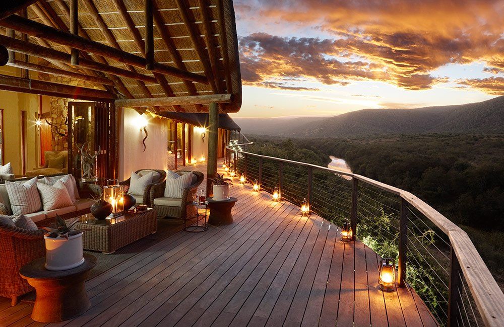 A large wooden deck with a view of a forest at sunset