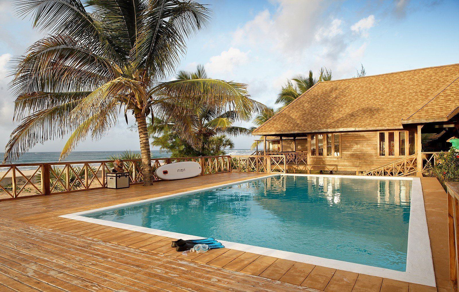 A large swimming pool surrounded by palm trees and a wooden deck