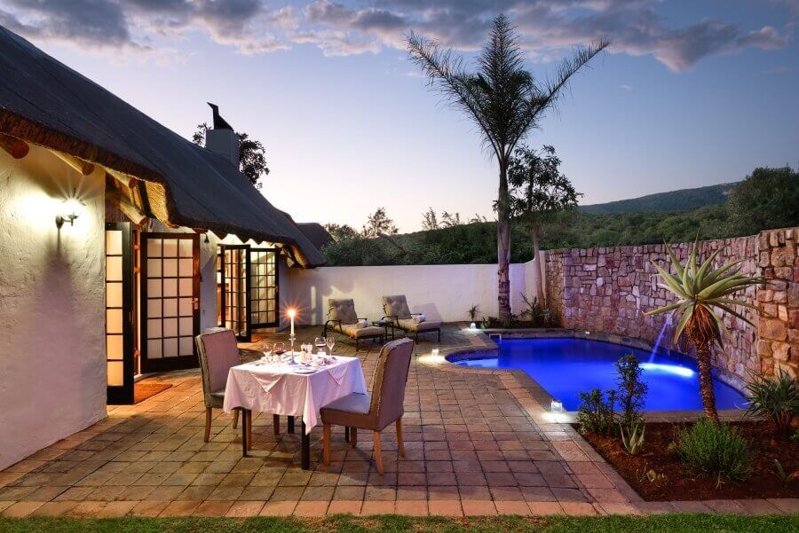 A patio with a table and chairs next to a swimming pool