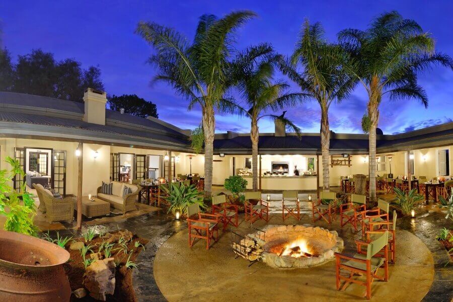 There is a fire pit in the middle of the courtyard surrounded by palm trees.