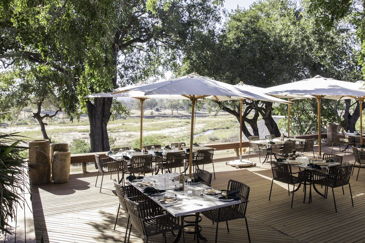 A patio with tables and chairs and umbrellas.