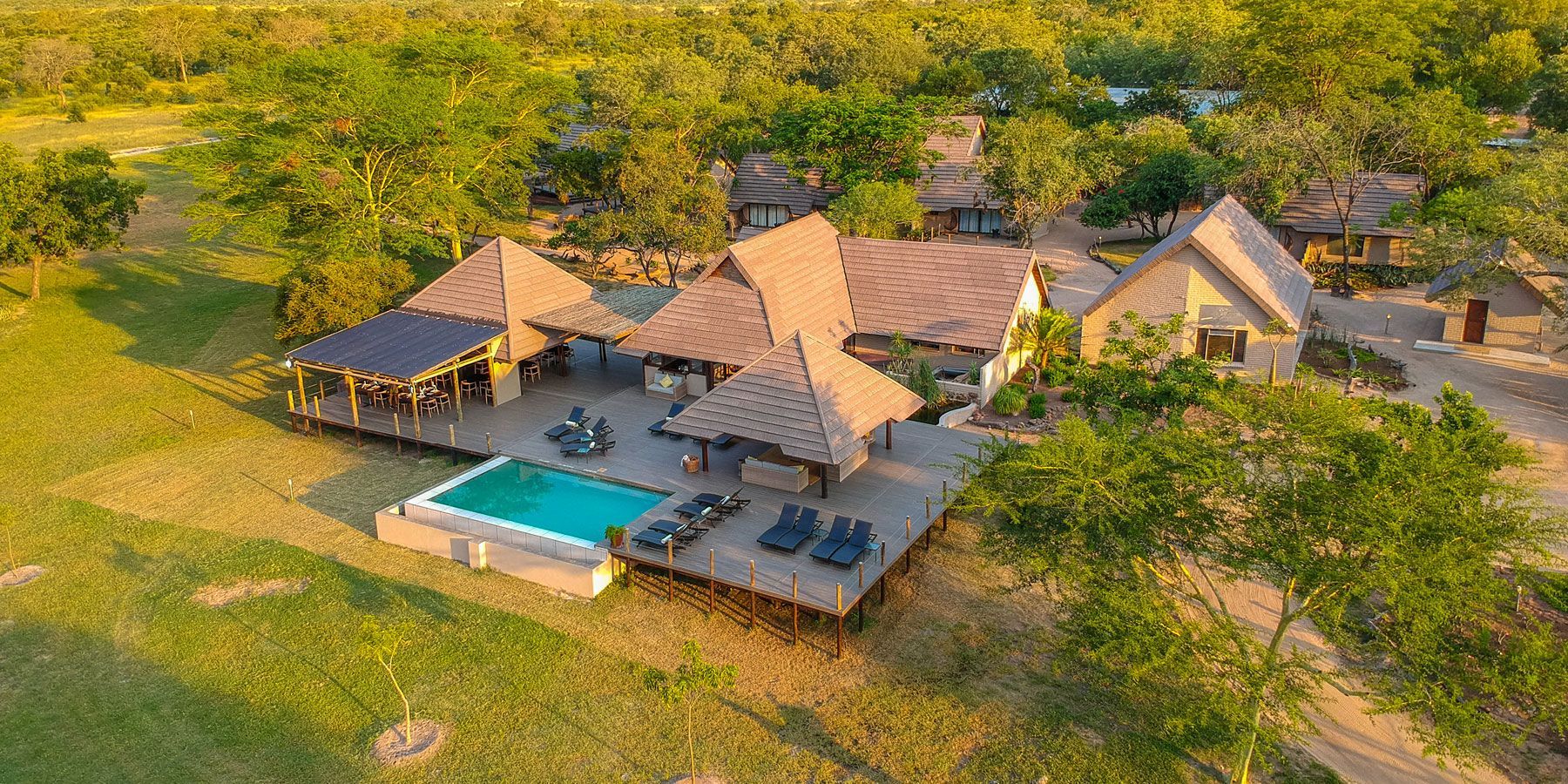 An aerial view of a large house with a swimming pool surrounded by trees.