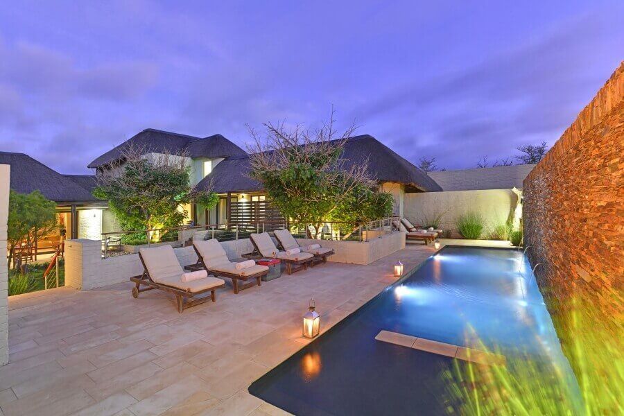 There is a large swimming pool in front of a house.