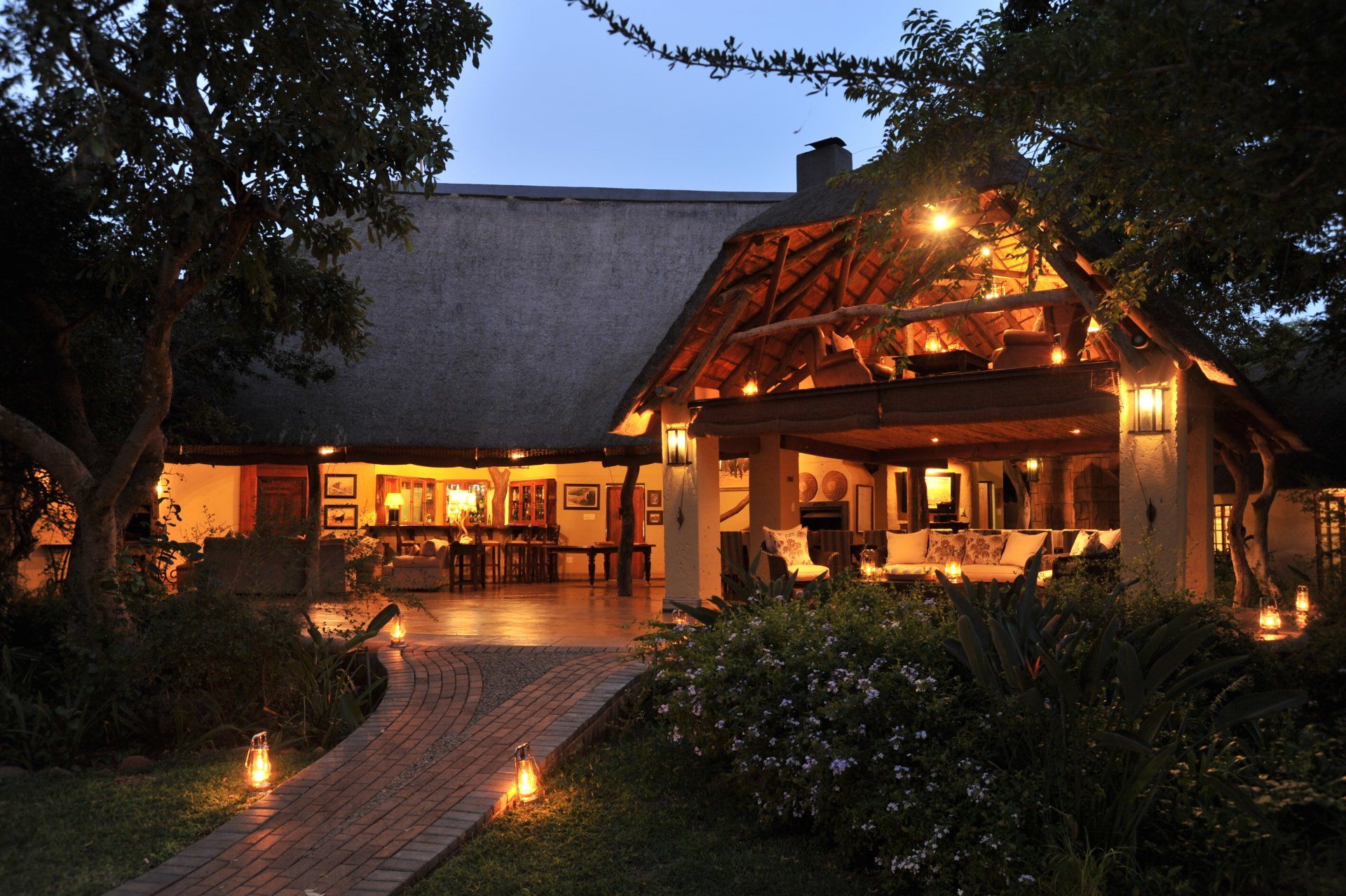 A large house with a thatched roof is lit up at night