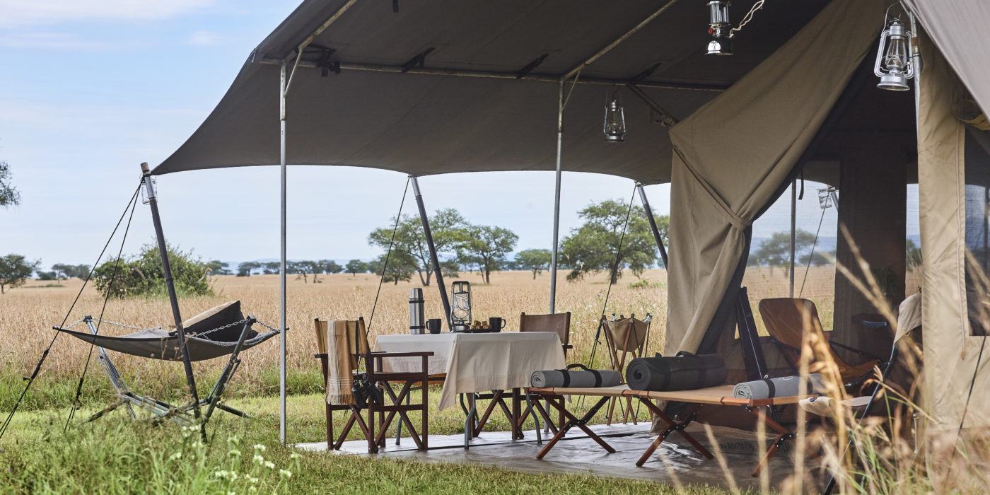 A tent with a table and chairs in the middle of a field.