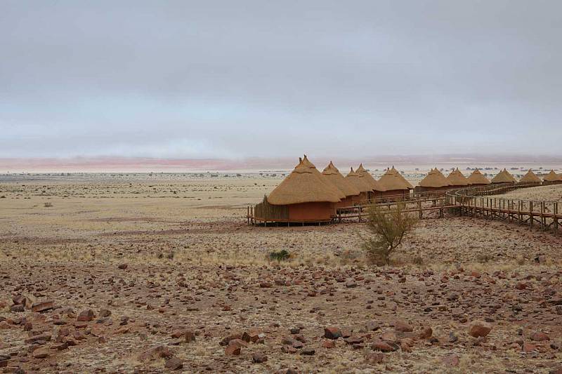 A row of thatched huts in the middle of a desert.