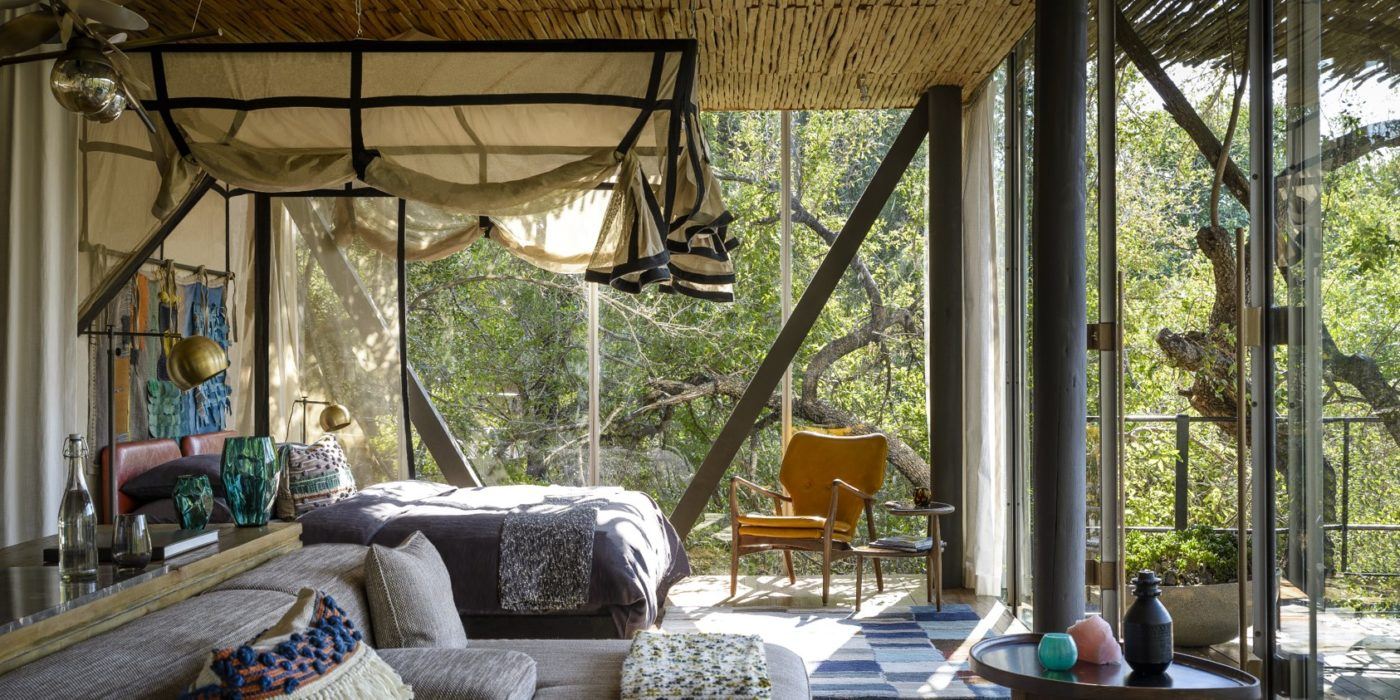 A living room with a bed , couch , chair and lots of windows.