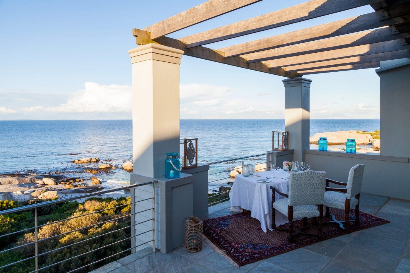 A table and chairs on a balcony overlooking the ocean.