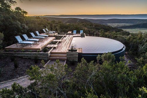 An aerial view of a large swimming pool surrounded by trees and chairs.