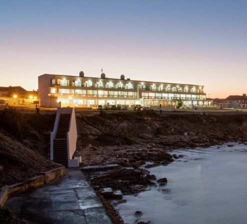 A large building is lit up at night next to a body of water.