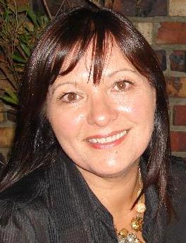 A woman with long dark hair is smiling and wearing a necklace.