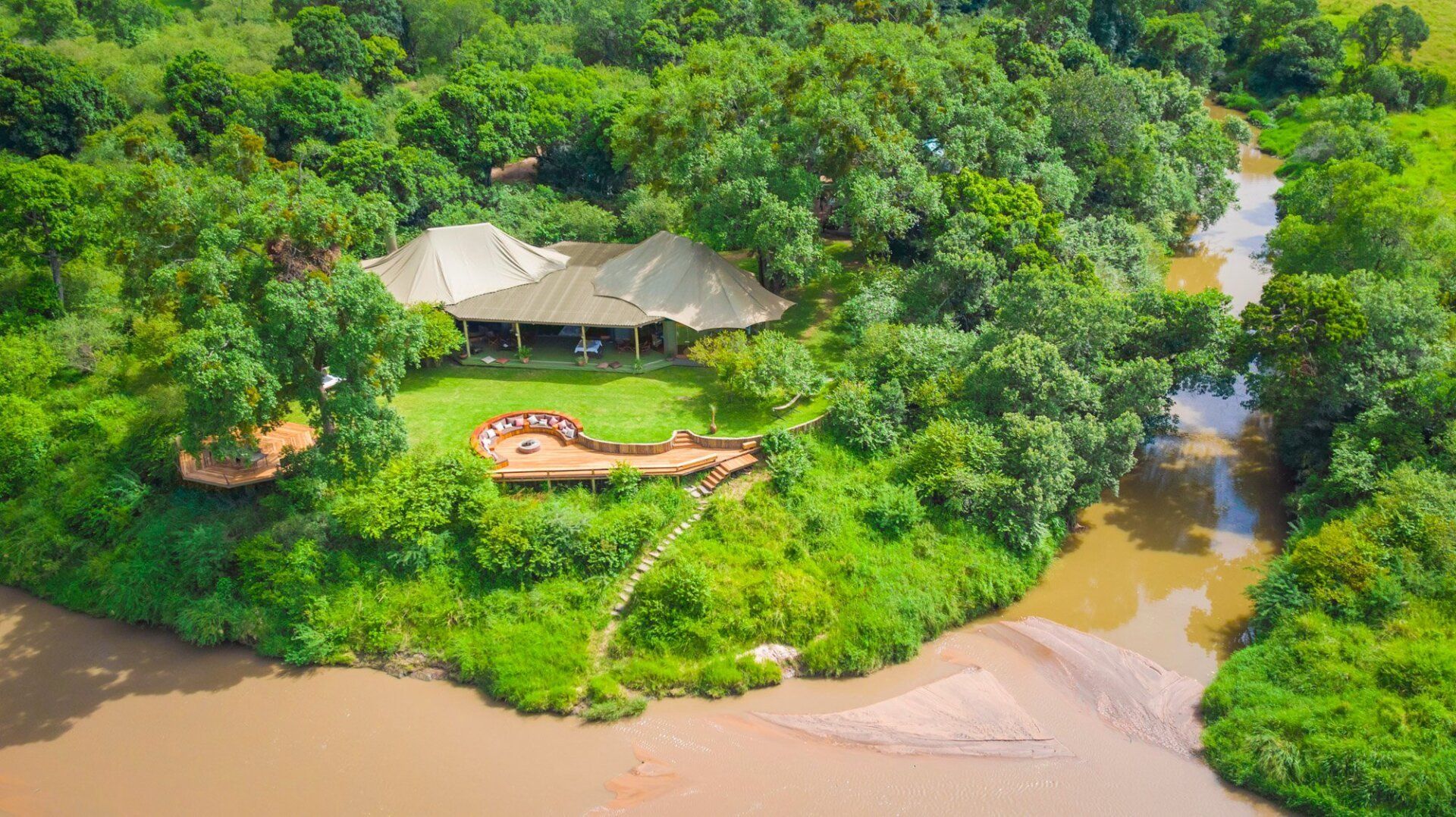 An aerial view of a house surrounded by trees next to a river.