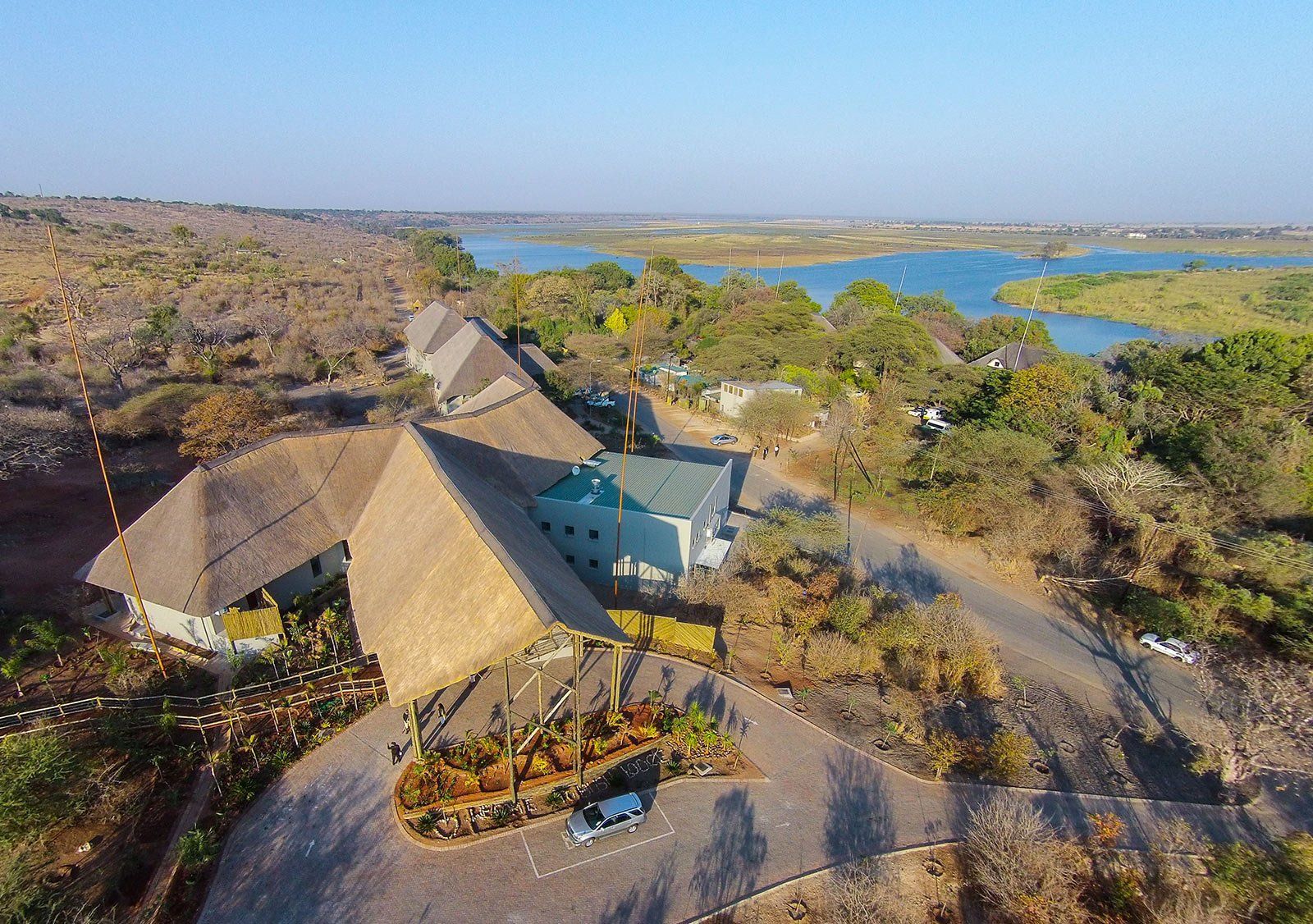 An aerial view of a house with thatched roofs and a lake in the background.