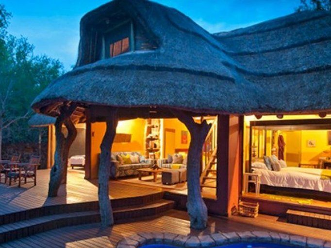 A house with a thatched roof and a swimming pool