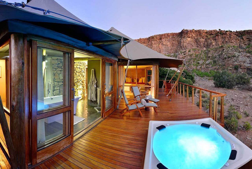 A hot tub is sitting on a wooden deck next to a tent.