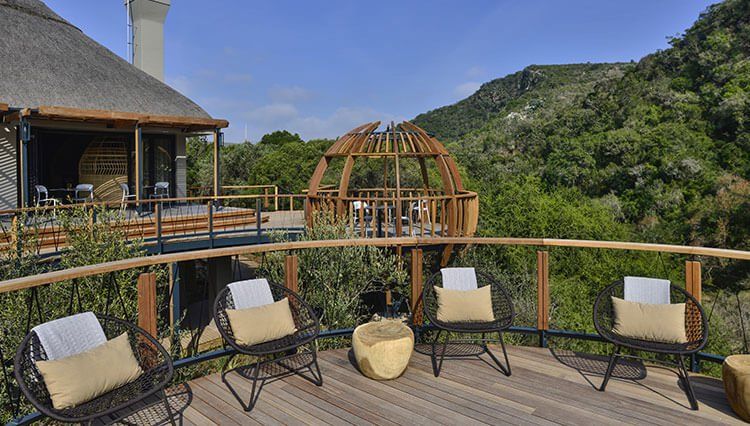 A wooden deck with chairs and a gazebo in the background.