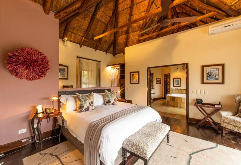 A bedroom with a king size bed and a thatched roof