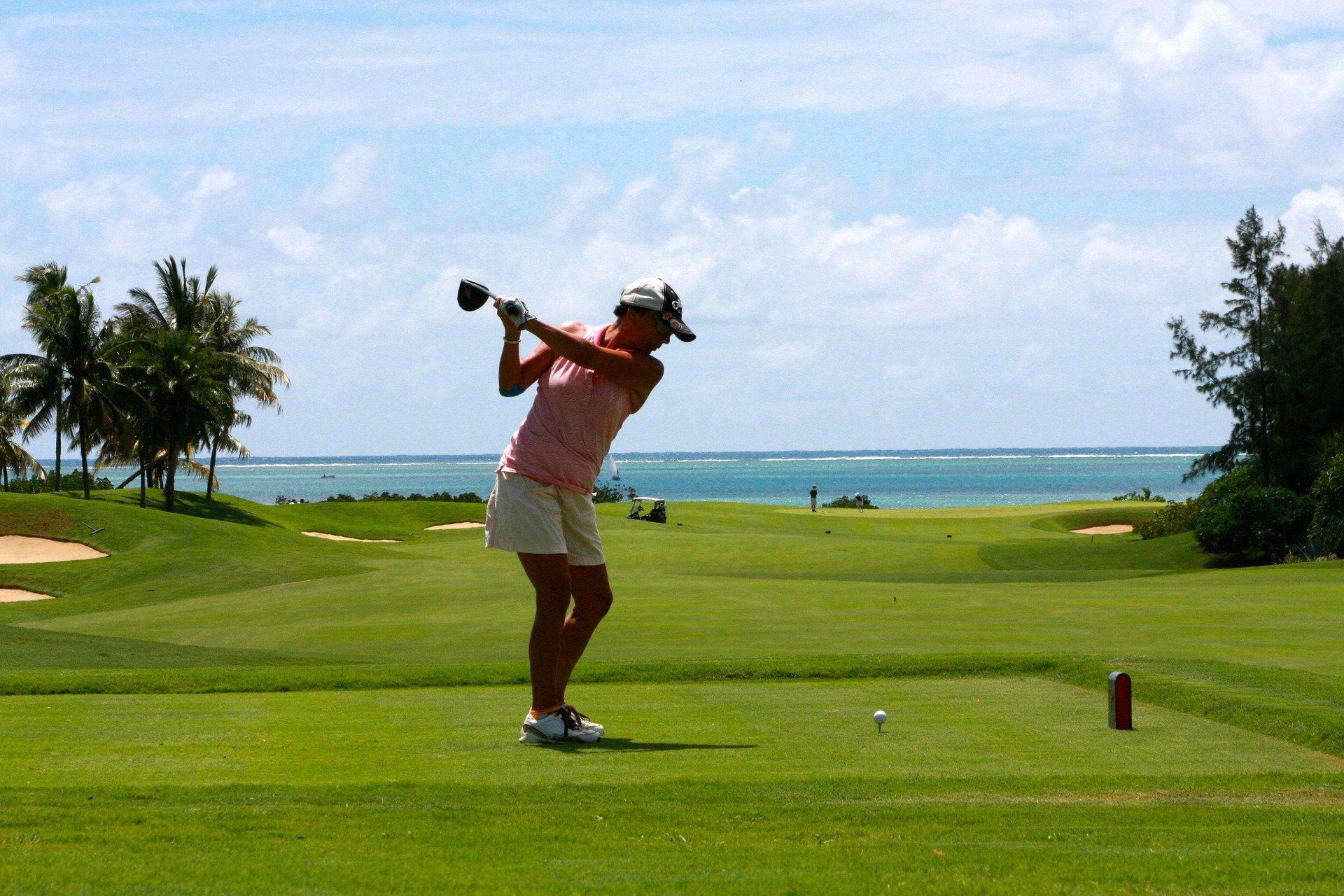 A woman is swinging a golf club on a golf course