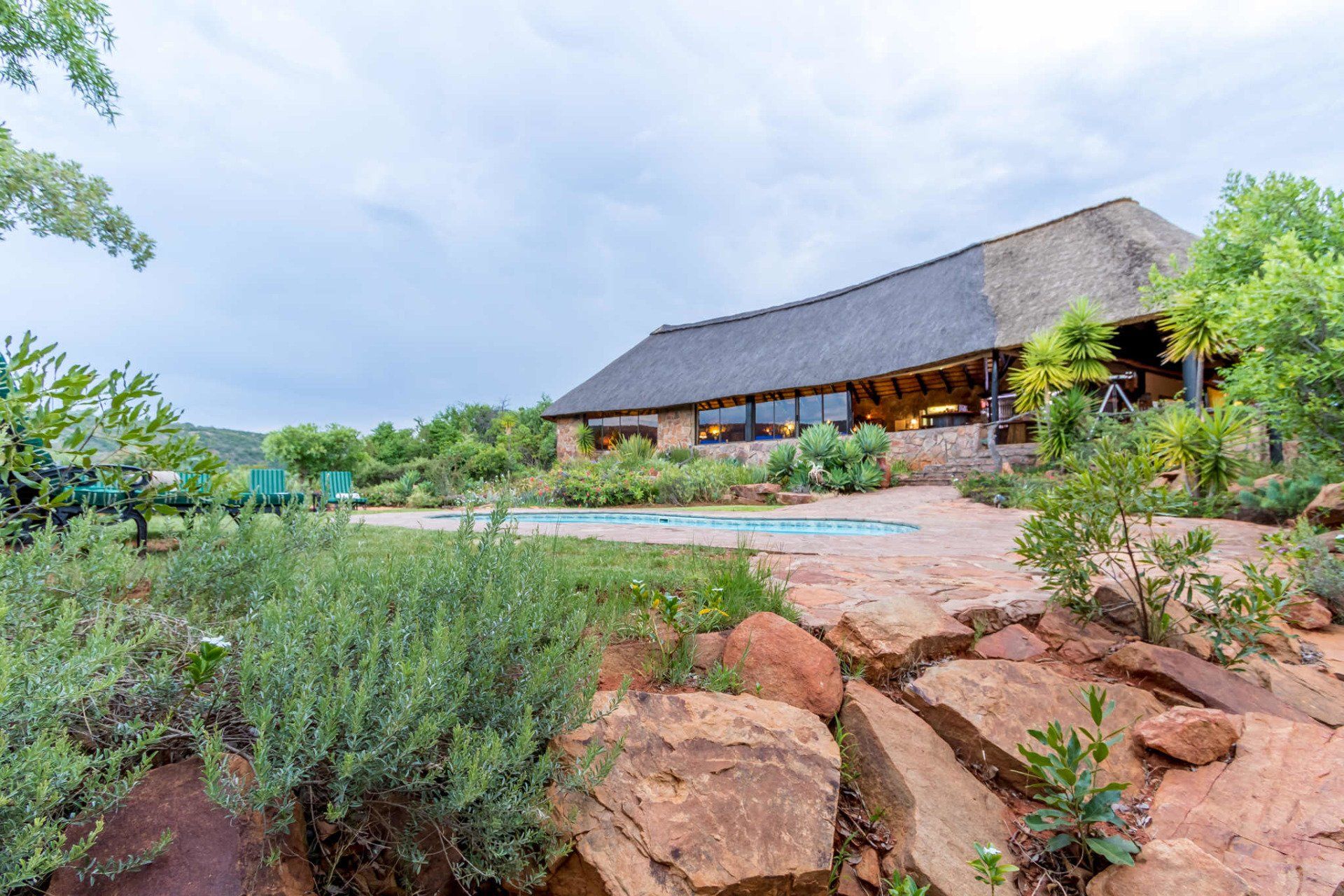 A large house with a thatched roof and a swimming pool in front of it.
