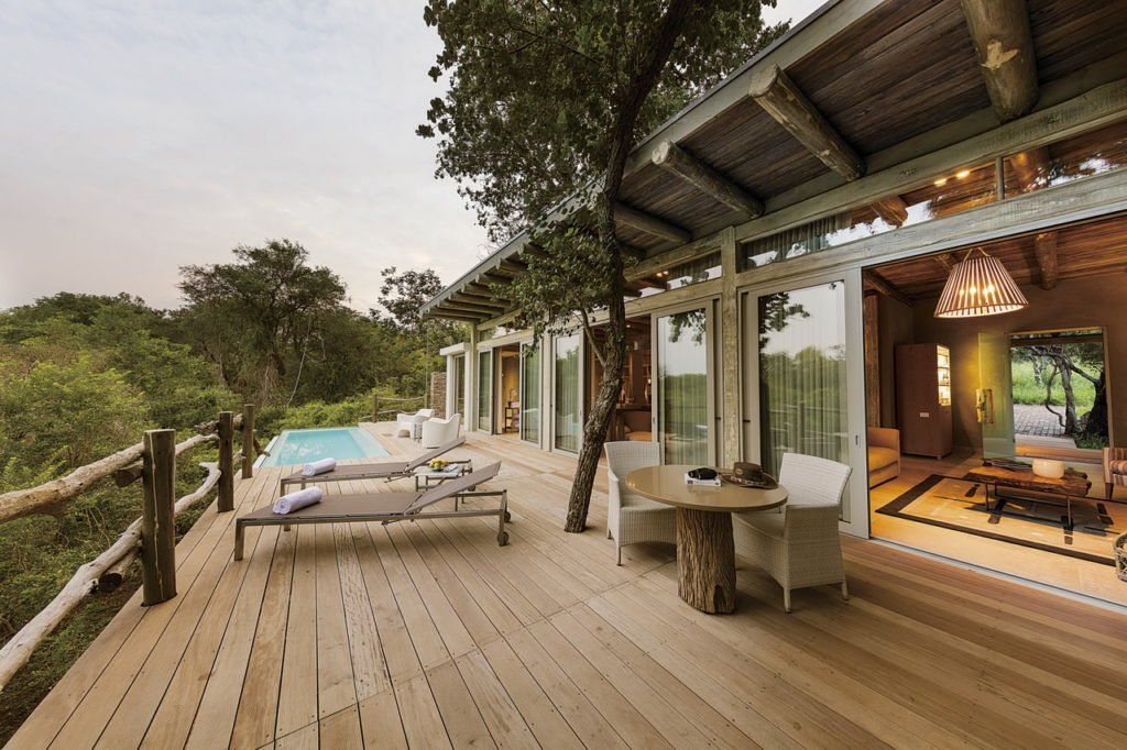 A large wooden deck with a swimming pool in the background