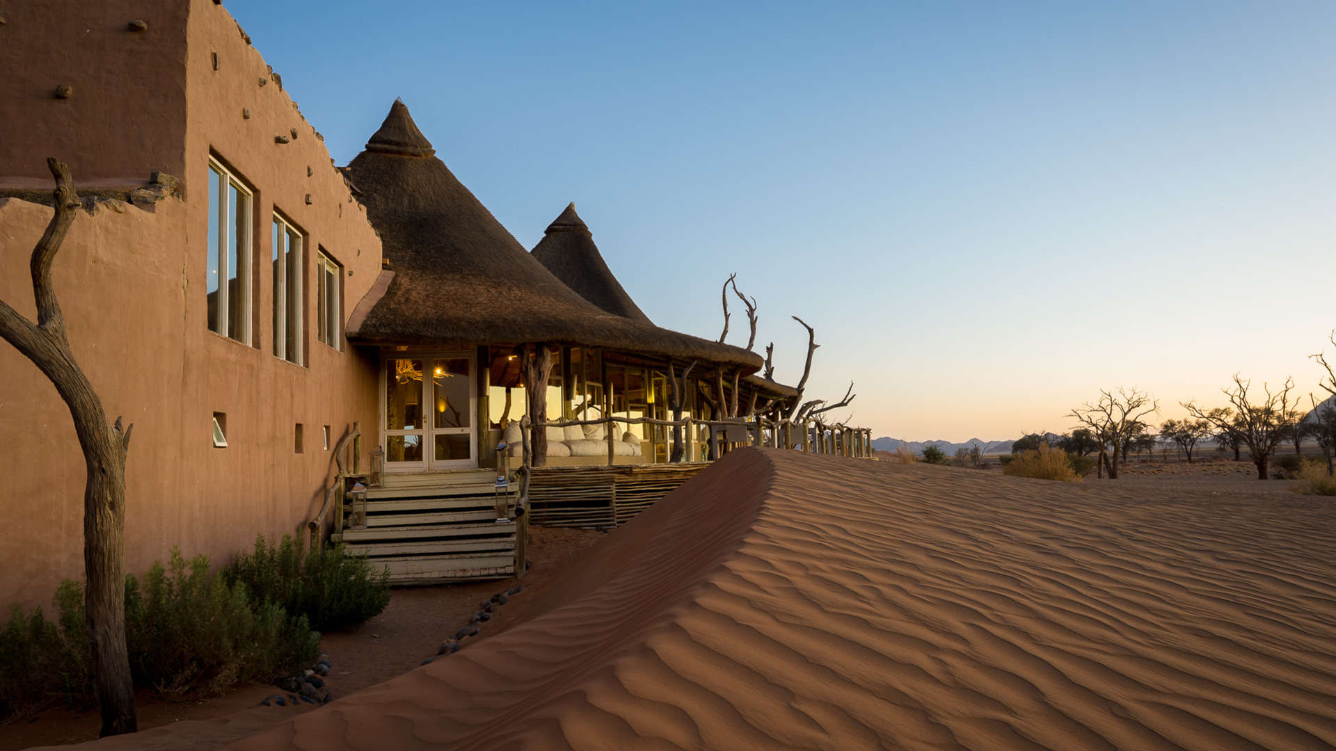 A building with thatched roofs in the middle of a desert.