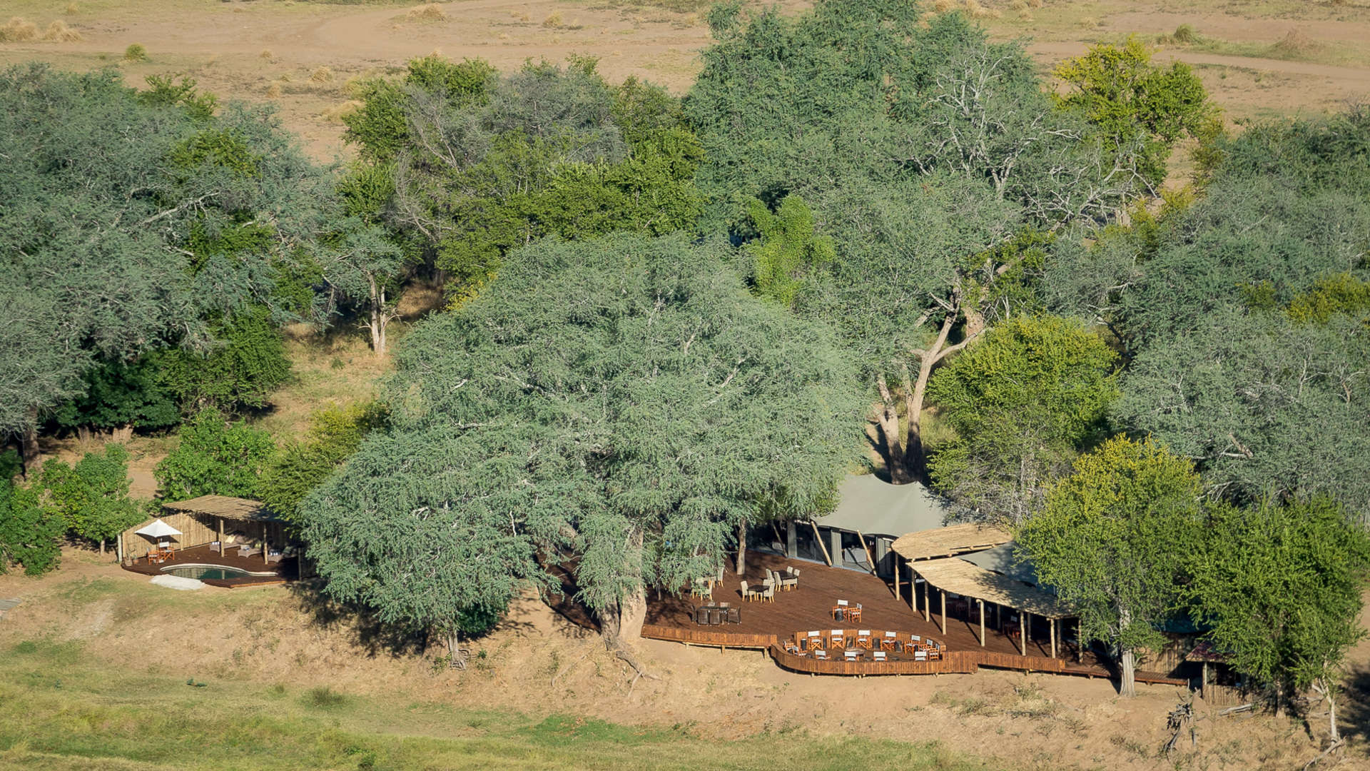 An aerial view of a house surrounded by trees in the middle of a field.
