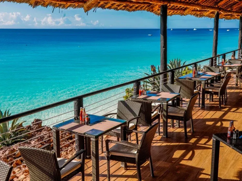 A restaurant with tables and chairs overlooking the ocean